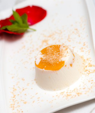 Beyaz tabakta İtalyan tatlı panna cotta Hindistan cevizi sütü ile dekore edilmiştir.