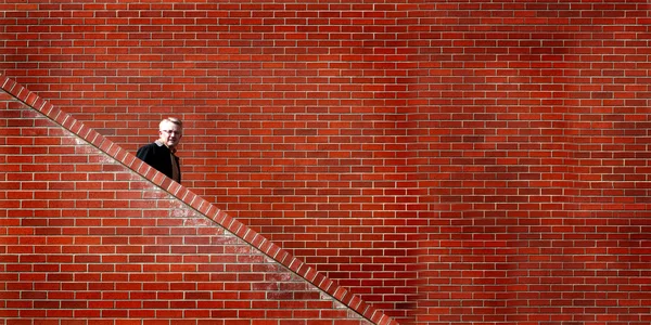Hombre Walking down Stairs Pared de ladrillo — Foto de Stock