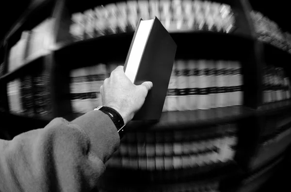 Χέρι εκμετάλλευση βιβλίο στη βιβλιοθήκη — Φωτογραφία Αρχείου