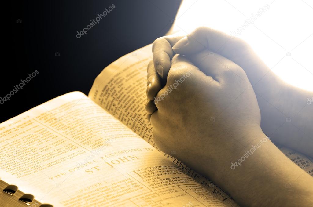 Hands Praying on Bible