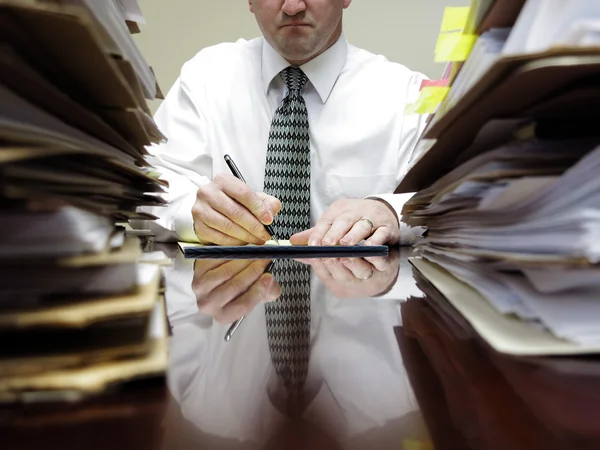 Geschäftsmann am Schreibtisch mit Aktenstapeln — Stockfoto