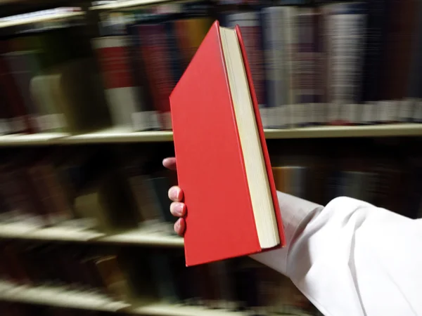 Libro rojo de mano en la biblioteca — Foto de Stock