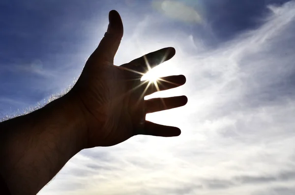 La mano della persona che raggiunge verso la luce del sole del cielo — Foto Stock