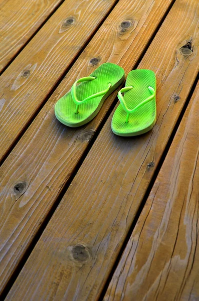 Chinelos verdes para o verão na plataforma de madeira velha — Fotografia de Stock