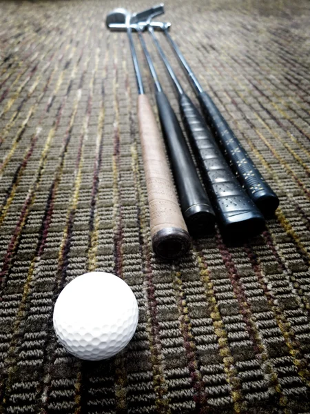 Golfklubbar och boll i office på mattan — Stockfoto