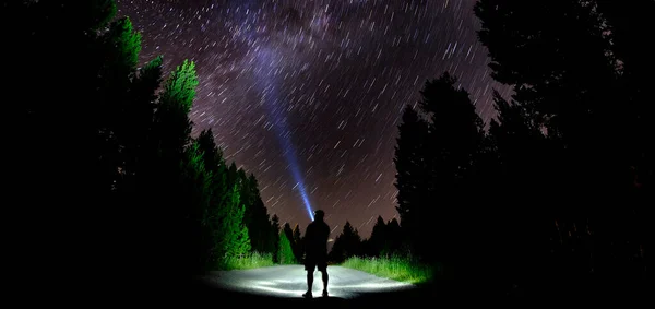 懐中電灯の森の夜空と星と暗闇の中に立つ男 — ストック写真