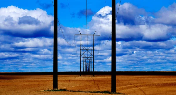 ユーティリティを表す青い空と雲のフィールド内の電力線 — ストック写真