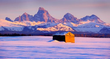 Teton Dağları, kışın Sunset Light Grand Tetons ve tarlada eski bir kulübe.