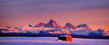 Teton Dağları, kışın Sunset Light Grand Tetons ve tarlada eski bir kulübe.