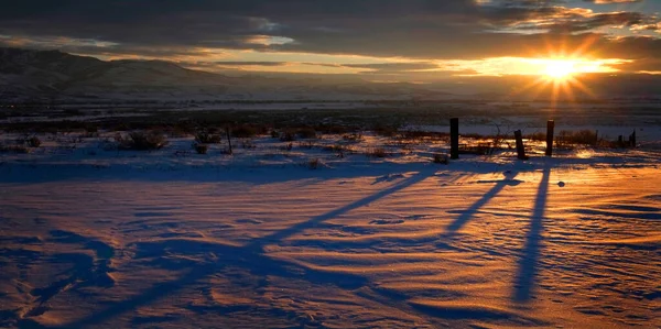 Sonnenaufgang Oder Sonnenuntergang Auf Zaunpfählen Werfen Schatten Über Den Schneebedeckten — Stockfoto