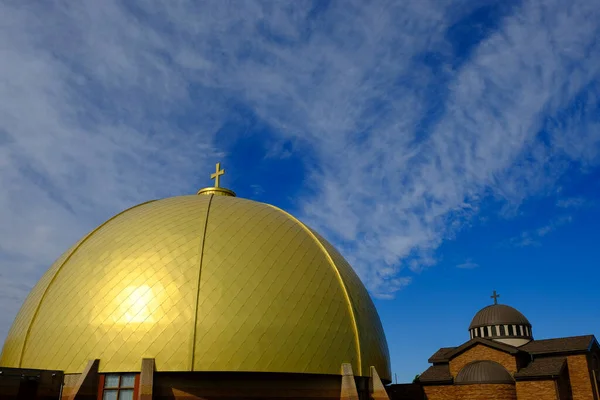 Gold dome on a christian church with cross and blue sky clouds in the background