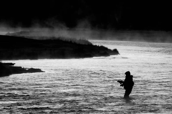 黄金の太陽の下で川で釣りフライフィッシングロッドリールのシルエット — ストック写真