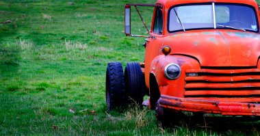 Eski hurda kırmızı iş kamyonu yeşil bir tarlada terk edilmiş.