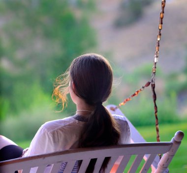 Girl on porch swing with soft summer evening light in hair
