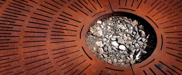 Rusty metal grate texture with rocks and soil in circle shape
