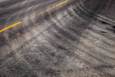 Lastik izleri sarı çizgili yolda dönüyor.