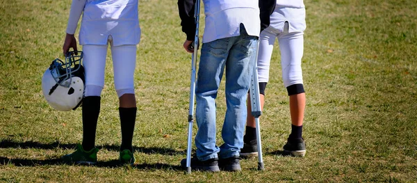 チームによる松葉杖を持つゲームのサイドライン上の負傷サッカー選手 — ストック写真