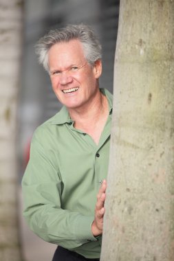 bir ağacın arkasından gülümsüyor mad