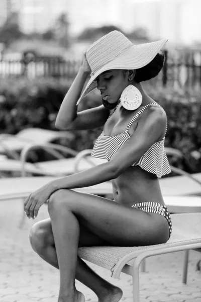 Черно-белое фото модели бикини, сидящей на шезлонге — стоковое фото