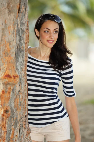 Stock image woman leaning on a tree in the park — Stock Photo, Image