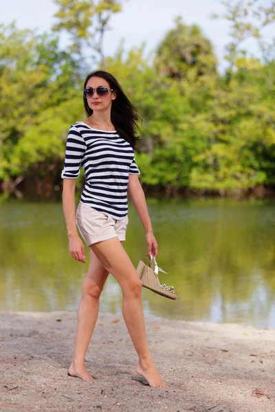 Vrouw in een natuurgebied instellen met schoenen in de hand — Stockfoto