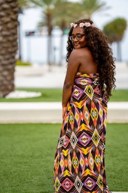 Tropikal bir ortamda renkli bir elbise içinde poz veren çok ırklı güzel bir kadın model.