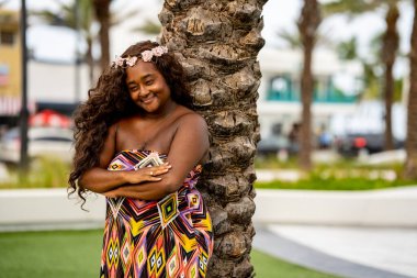 Tropikal bir ortamda renkli bir elbise içinde poz veren çok ırklı güzel bir kadın model.