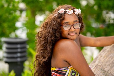 Tropikal bir ortamda renkli bir elbise içinde poz veren çok ırklı güzel bir kadın model.