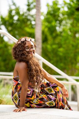 Tropikal bir ortamda renkli bir elbise içinde poz veren çok ırklı güzel bir kadın model.
