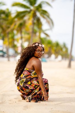 Tropikal bir ortamda renkli bir elbise içinde poz veren çok ırklı güzel bir kadın model.