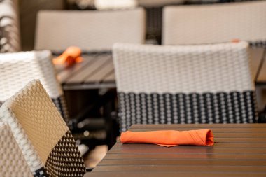 Portakal rengi peçeteye sarılı yemek masaları.