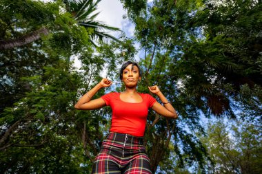 Parkta poz veren güzel bir kadın modelin fotoğrafı. Güç gösteren güçlü kollar.