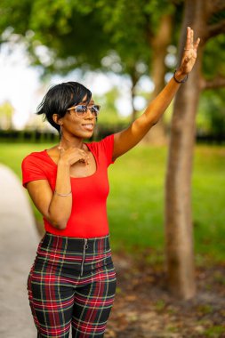 Parkta poz veren güzel bir kadın modelin fotoğrafı. Arkadaşlarına el sallıyorsun.. 