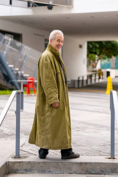 Oude Man Poserend Een Groene Oversized Trenchcoat — Stockfoto