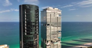 Siyah Porsche Tasarım Kulesi ve Beyaz Turnberry Ocean Club Residences. 5k drone yükselen görüntü