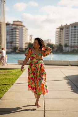 Çekici bir kadın kameraya doğru yürüyor ve uzaklaşıyor.