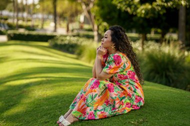 Yeşil çimen tarlasında oturan genç bir kadın resmi