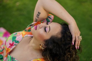 Güzel bir kadın, tensel bir pozda, elleri kafasında.