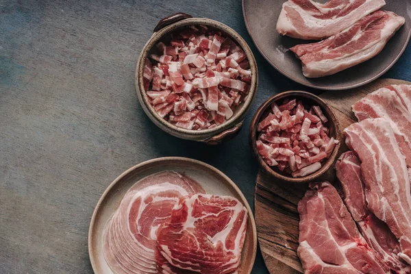 Variety of high fat meat products. Uncooked ribs with spiringue, piece of pork loin, ham, lard, pancetta, bacon on the table, top view