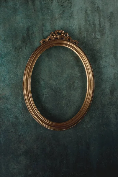 Vintage gold oval frame on a old wall background