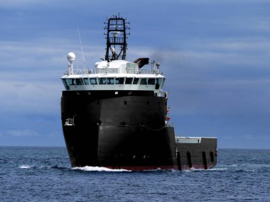 Offshore supply vessel underway to offshore installation. clipart