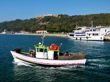 Deniz manzaralı balıkçı teknesi ve kale zeminli turist teknesi.