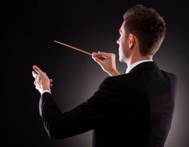 Back view of a young composer directing with his baton clipart