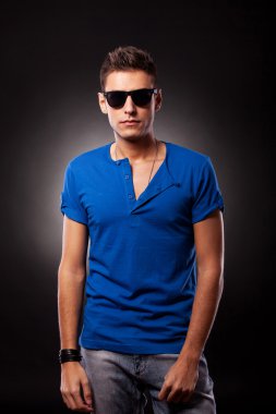 Mavi t-shirt ve güneş gözlüğü takan genç adam modeli