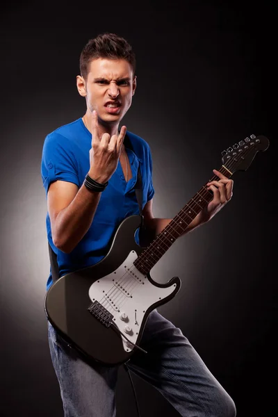 Młody człowiek z gitara elektryczna Wyświetlono rock and rolla znak — Zdjęcie stockowe