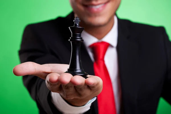 Rei negro do xadrez na palma de um jovem homem de negócios — Fotografia de Stock