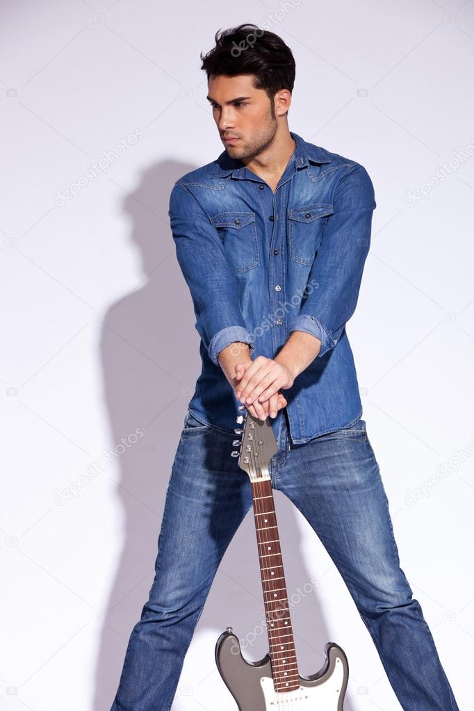 casual man holding a guitar on the ground