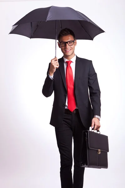 Sorridente homem de negócios sob um guarda-chuva andando — Fotografia de Stock