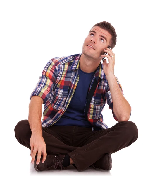Młody człowiek w telefonie siedzi wyszukuje — Zdjęcie stockowe