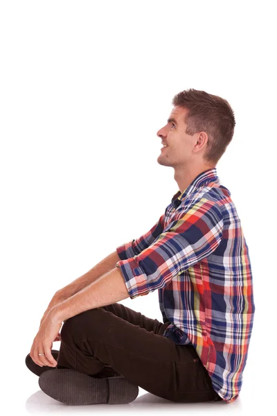 Mladý muž sedí s rukama na kolenou — Stock fotografie